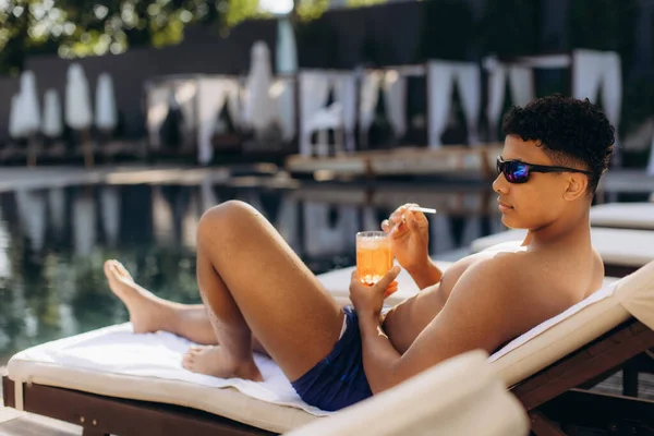 Havuz kenarında dinlenen turistler, güneşli bir kokteylin tadını çıkarırken aynı zamanda mükemmel bir yaz tatili boyunca lüks bir tatil köyünde güneşleniyorlar.