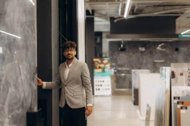 Gri takım elbiseli bir profesyonel modern bir galeride şık iç tasarımlarıyla duruyor, işlevsellik ve estetiği mimari ve tasarımda birleştirmek için yaratıcı fikirleri keşfediyor..