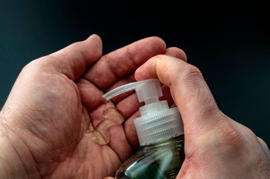 Bakterilerden, kişisel hijyenden ve grip koruma kavramından korunmak için koyu siyah arka planda izole edilmiş alkole dayalı el dezenfektanı jeli kullanın.