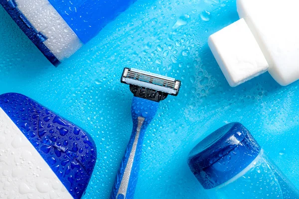 Men cosmetic products, personal hygiene and male hair care and shaving concept with kit of masculine shampoo, aftershave, body wash, gel and razor soaked in water droplets on wet light blue background