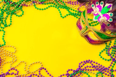 Yağlı Salı ve Mardi Gras karnaval konsepti teması. Renk, tüy, doku, altın, yeşil ve mor boncuklarla dolu bir yüz maskesiyle yakın plan.