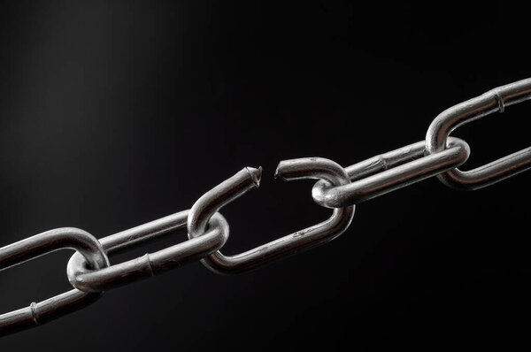 The team is as strong as its weakest link and single point of failure concept with powerful iron chain with one stressed link breaking under physical pressure isolated on black background