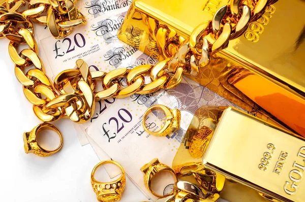Jewelry buyer, pawn shop and buy and sell precious metals concept theme with pile of cash in british pounds, golden rings, necklace bracelet and gold bullion isolated on white background