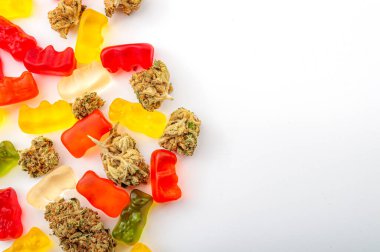 Esrar yenilebilir, tıbbi marihuana, CBD aşılanmış jelibon ve renkli jelibon ayıları ve beyaz arka planda fotokopi alanı olan ot tomurcukları ile yakın plan ile yenilebilir ot konsepti teması