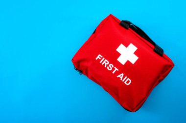 İlk yardım ve tıbbi acil müdahale kavramı beyaz haçlı bir kırmızı ve mavi arka planda izole edilmiş bir ilk yardım çantasının düz görünümü ile metin için metin alanı ile.