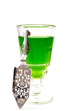 Alkolik içecek, yaratıcı uyarıcı ve bohem yaşam tarzı konsepti. Beyaz arka planda izole edilmiş yeşil absent ve paslanmaz çelik kaşık.