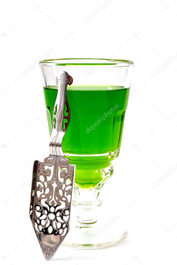 Alcoholic drink, creative stimulant and bohemian lifestyle concept theme with glass of green absinthe and stainless steel spoon isolated on white background