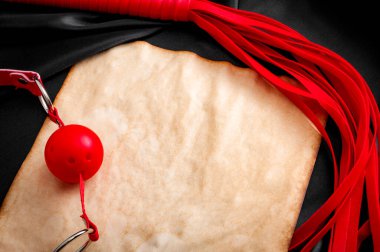 Hedonizm, yetişkin oyunları ve kırmızı top şakası ve deri kırbaçlayıcı ile BDSM yaşam tarzı konsepti, siyah ve koyu gri tonlarında parlak ipek üzerine bir kağıt parçası etrafında bir sınır oluşturuyor.