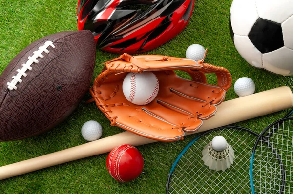 Sports shop, youth athletics and team sport competition conceptual idea with various types balls (soccer, baseball, football, golf ball), wooden bat and bike helmet isolated on green grass background