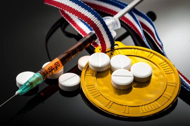 Spor ve steroid bağımlılığı kavramında altın madalya, reçeteli haplar ve karanlık arka planda bir şırınga.
