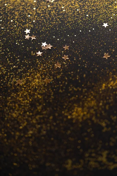 Hermoso fondo de luz de Navidad. Bokeh brillo abstracto y destellos dispersos en oro, en negro —  Fotos de Stock