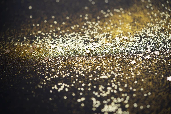 Beautiful Christmas light background. Abstract glitter bokeh and scattered sparkles in gold color, on black — Stock Photo, Image