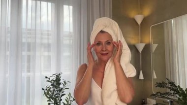 Neşeli bir kadın huzurlu, bitkisel banyosunda cilt bakımının keyfini çıkartıyor.