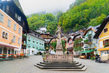 Göz kamaştırıcı dağlarla yukardaki bulutlar arasında güzelce yuva yapmış güzel bir Hallstatt göl kenarı köyü, Avusturya