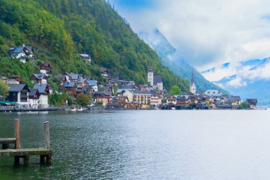 Göz kamaştırıcı dağlarla yukardaki bulutlar arasında güzelce yuva yapmış güzel bir Hallstatt göl kenarı köyü, Avusturya