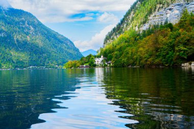 Göz kamaştırıcı dağlarla yukardaki bulutlar arasında güzelce yuva yapmış güzel bir Hallstatt göl kenarı köyü, Avusturya