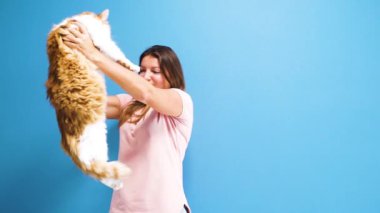 Büyük, yumuşak, beyaz ve kırmızı bir kedi tutan kadın.