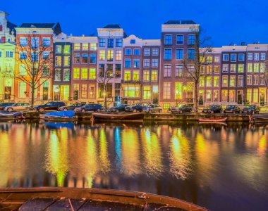 Tipik Hollanda evleri ile ışıklı windows yansımaları su ile kanal üzerinden geceleri, Amsterdam, Hollanda