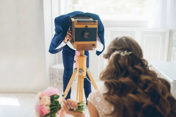 The groom photographs the bride on a vintage camera — Stock Photo, Image