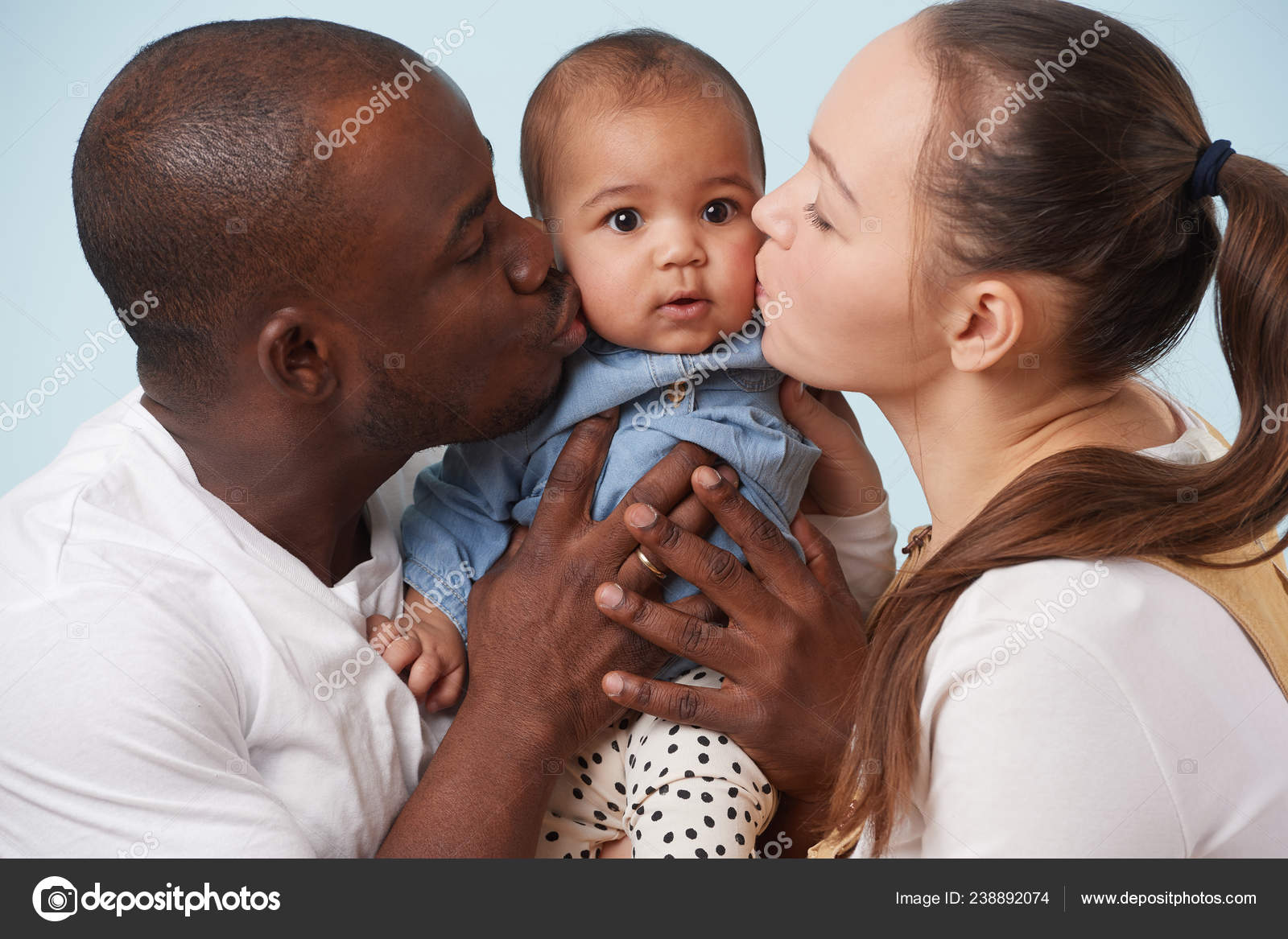 多民族の幸せな家族の肖像画 白の母 黒人の父と淡いブルーの背景に愛らしい小さな赤ん坊の娘 両方の親は 自分の娘は それぞれ つの頬にキス ストック写真 C Zzzdim