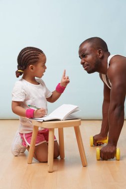 Sevimli küçük kızı fitness notlar yakışıklı siyah genç babası, eğitim. Çocuk rol yapma. Ona parmağını kaldırdı yorum olduğunu iken sitemler dinleme görünüyor.