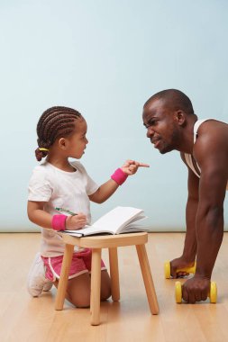 Sevimli küçük kızı fitness notlar yakışıklı siyah genç babası, eğitim. Çocuk rol yapma. Ona, ona parmağını puan iken sitemler dinleme bakar.