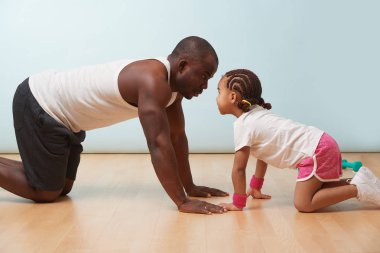 Yakışıklı siyah genç baba ve sevimli küçük kızı dört ayak üzerinde birlikte evde yerde uzanan duruyor. Onlar birbirlerine yüz yüze arıyoruz.