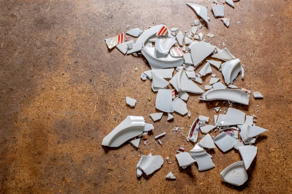 Trozos de platos destrozados. Fragmentos de la vajilla blanca rota en el suelo . — Foto de Stock