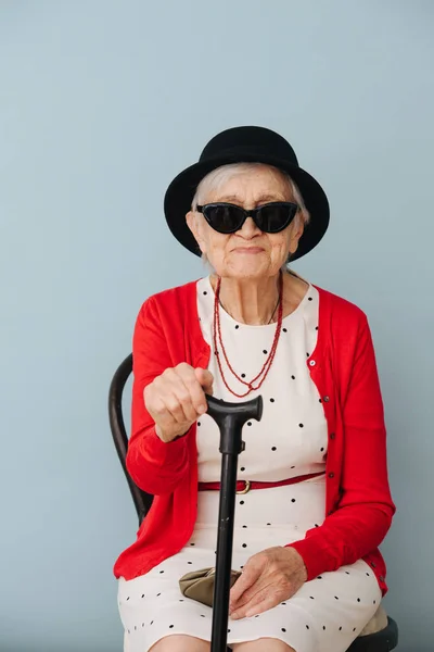 Senior, colorfully dressed woman is resting on a chair at home — Stock Photo, Image