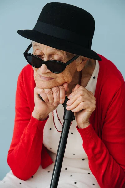 Senior, colorfully dressed woman is resting on a chair at home — Stock Photo, Image