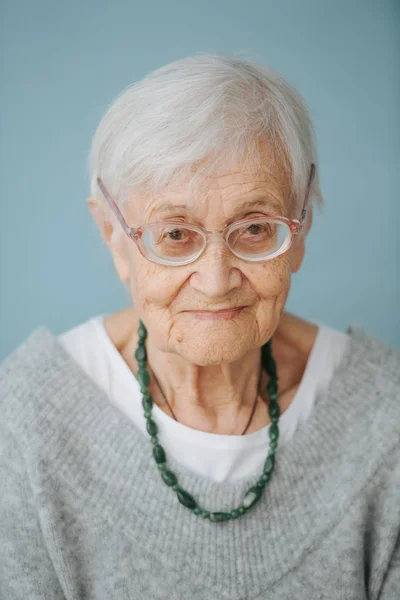 Portrait of elderely grey haired woman in a comfortable sweater at home — Stock Photo, Image