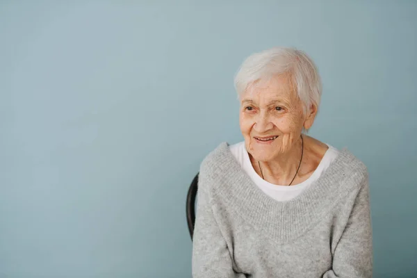 Portrait of elderely grey haired woman in a comfortable sweater at home — Stock Photo, Image