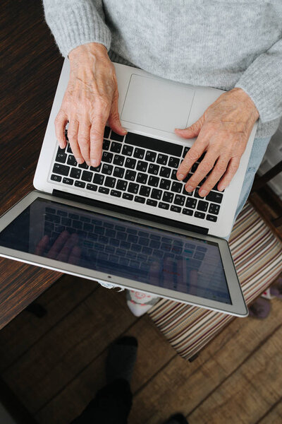 Руки пожилой женщины, просматривающей ноутбук
