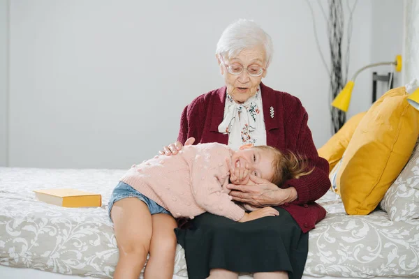 Des moments heureux. Petite fille avec son arrière grand-mère passer du temps de qualité ensemble Images De Stock Libres De Droits