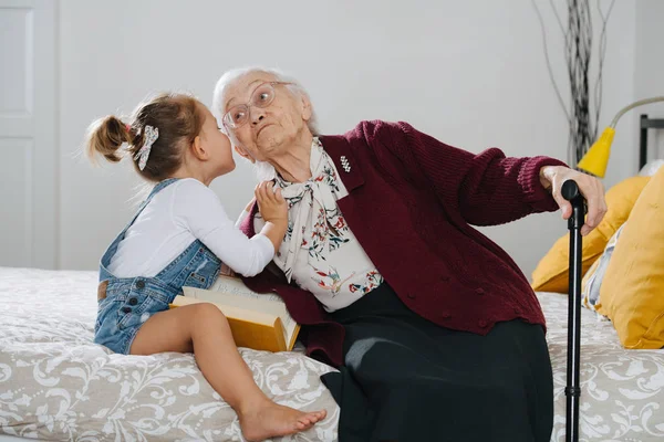 Des moments heureux. Petite fille avec son arrière grand-mère passer du temps de qualité ensemble Photo De Stock