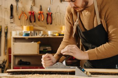 Marangoz bir atölyede sipariş mobilya yapıyor.