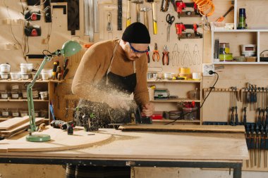 Marangoz bir atölyede sipariş mobilya yapıyor.