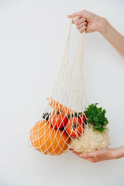 Mãos segurando legumes no saco de cordas — Fotografia de Stock