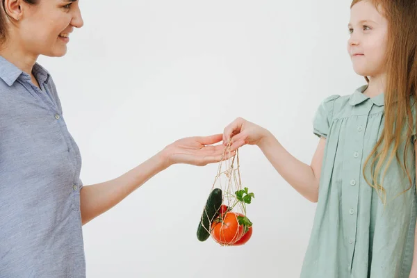 Мама дає їй дочку струнний мішок з овочами — стокове фото