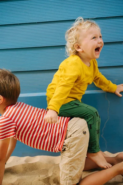 Outdoor portrait of big brother and his little sister against blue house wall — Stock Photo, Image