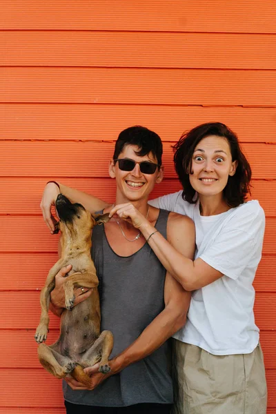 Felice bella coppia condividere la loro gioia contro muro casa arancione . — Foto Stock