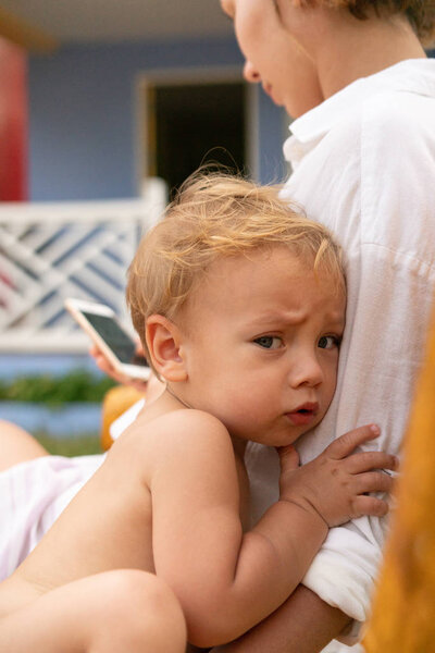 Малыш Тоддлер страшно обнимает мать за плечо.
.