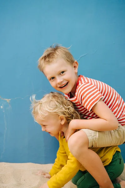 Outdoor portrait of big brother and his little sister against blue house wall — Stock Photo, Image