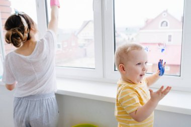 Bir bebek çocuk annesi ıslak bez ile plastik pencere kapısı temizlik