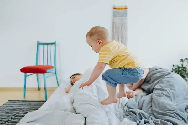 Cute little son trying to wake up his parents. — Stock Photo, Image