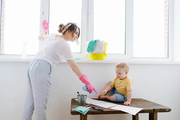 Bir bebek çocuk annesi ıslak bez ile plastik pencere kapısı temizlik — Stok fotoğraf