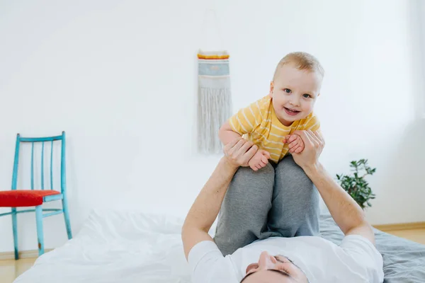 Young father is playing with his little toddler baby in parents bedroom — Stock Photo, Image