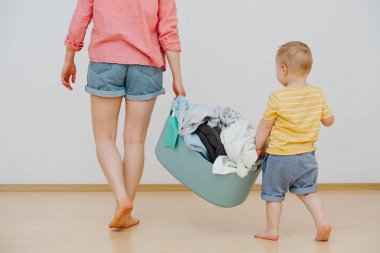 Genç anne ve onun mutlu küçük oğlu çamaşır leğeni dolusu havluyla