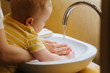 Küçük yürümeye başlayan çocuk ve annesi banyo lavaboellerini yıkayın