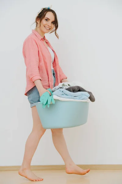 Young happy woman with laundry basin full of washed towels — Stock Photo, Image
